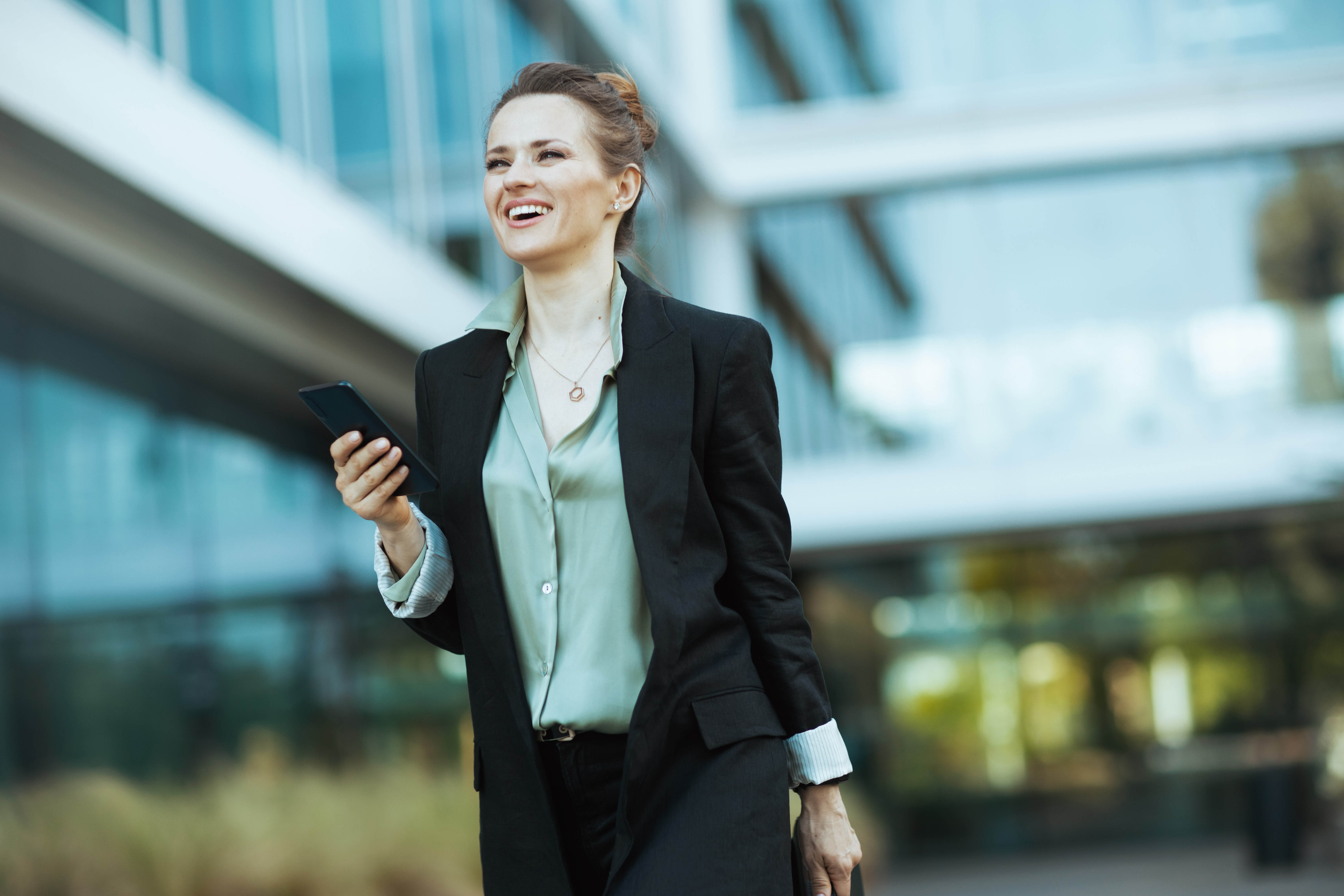 Business woman taking a walk outside with her phone during the work day